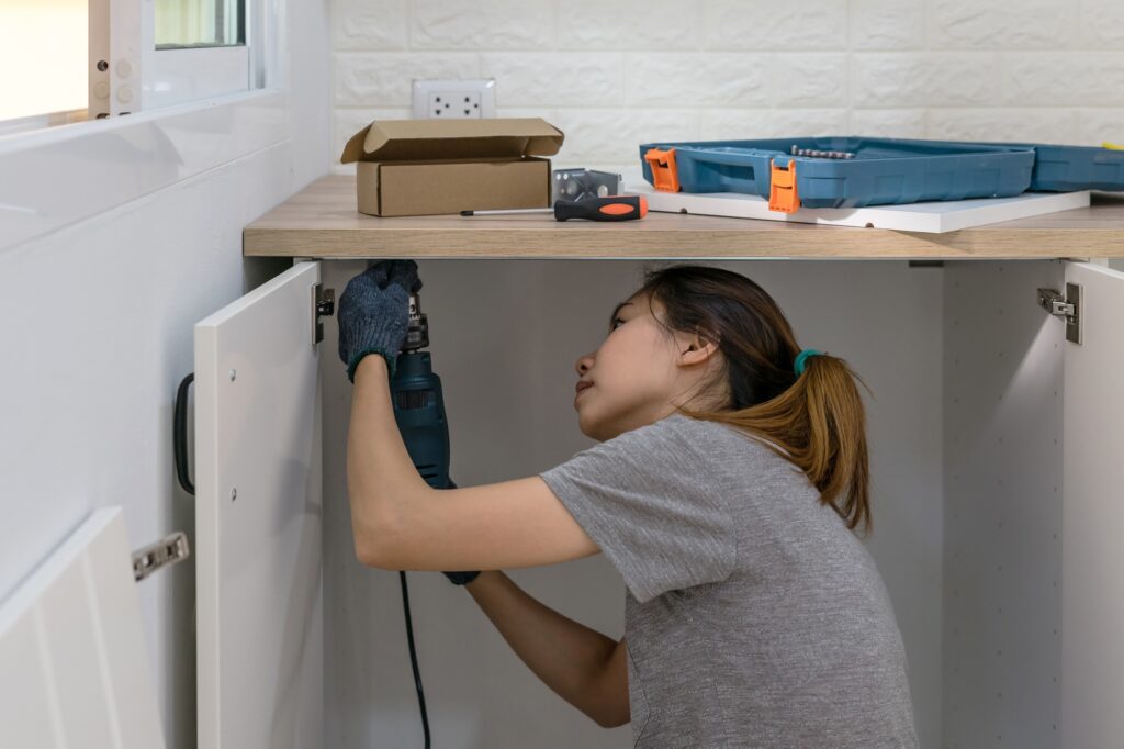 Young woman using electric screwdriver to installation